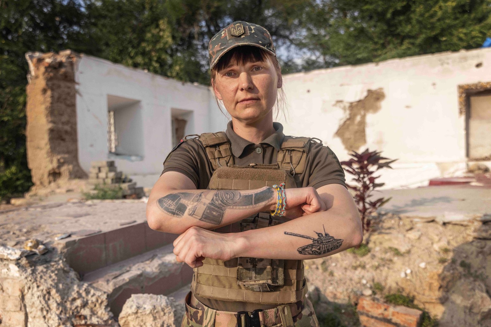 Helena Maksyom in uniform, arms crossed, showing tattoos of a camera and a tank